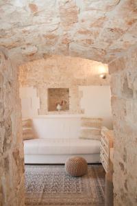 a room with a white bed in a stone wall at EnjoyTrulli - Countryside in Noci