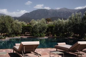 two chairs and a swimming pool with mountains in the background at Olinto, Atlas Mountain Retreat - adults only in Ouirgane
