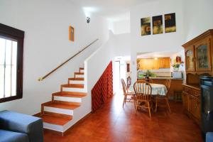 sala de estar con escaleras, mesa y cocina en Casas Rurales Juzcar Centro, en Júzcar
