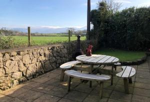 a picnic table and benches with a stone wall at 4 Bed Farmhouse - Pets - Garden - Parking in Beaumaris