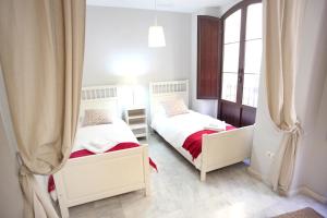 two beds in a room with two windows at Sleepin Sevilla in Seville