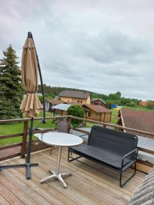 a patio with a table and an umbrella on a deck at Pas Daivą in Šventoji