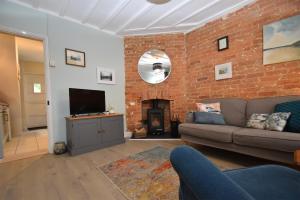 a living room with a couch and a brick wall at Honey Cottage in Rye