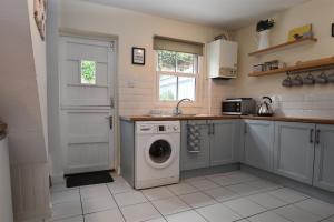 a kitchen with a washing machine and a sink at Honey Cottage in Rye