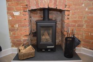 a wood stove in a brick wall at Honey Cottage in Rye