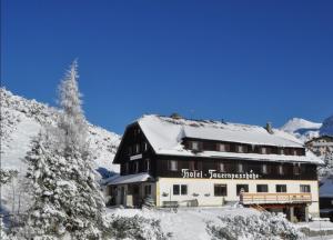 un grand bâtiment avec de la neige sur le toit dans l'établissement Hotel Tauernpasshöhe, à Obertauern