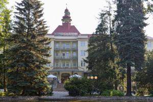 un grand bâtiment blanc avec un toit rouge dans l'établissement Apartament przy deptaku i Parku Zdrojowym - Polanica Zdrój, à Polanica-Zdrój