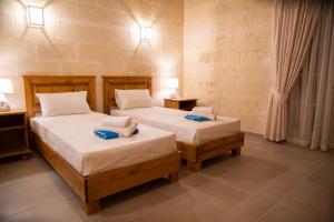 two beds in a room with two tables and two lamps at Ta' Ganna Farmhouse in Sannat