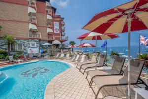 a pool with chairs and umbrellas next to a building at Hotel Firenze 3 Stelle Superior in Brenzone sul Garda