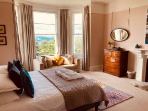 a bedroom with a bed and a couch and a window at Highleigh House in Teignmouth