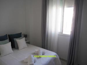 ein Schlafzimmer mit einem Bett mit weißen Kissen und einem Fenster in der Unterkunft Jimios Alcázar Catedral in Sevilla