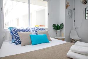 a white bedroom with blue and white pillows on a bed at GoToSeville Molviedro Apartments in Seville