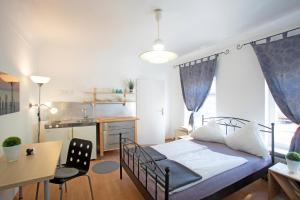 a bedroom with a bed and a desk and a kitchen at Hostel Westküste in Lindau