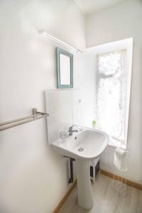 baño blanco con lavabo y ventana en Le First - proche Naval Group -, en Cherbourg-en-Cotentin