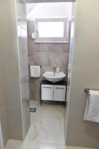 a bathroom with a sink and a shower with a window at Studio Apartments Kamicak in Sinj