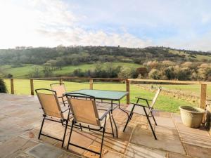 a table and chairs on a patio with a view of a field at North View Cottage - Log burner,Views,Parking,walks,Peak District,Dogs in Rainow