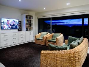 a living room with two chairs and a flat screen tv at Oke Beach House - Rawhiti Luxury in Rawhiti