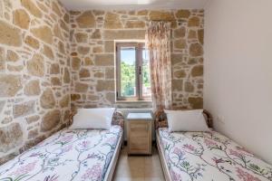 two beds in a room with a stone wall at Dream house near the beach in Drapaniás