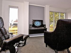 uma sala de estar com uma televisão, um sofá e uma cadeira em Handbridge - Ohakune Holiday House em Ohakune