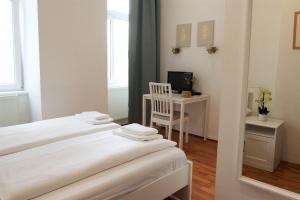 2 Betten in einem Zimmer mit einem Schreibtisch und einem TV in der Unterkunft Hotel Pension ARPI in Wien