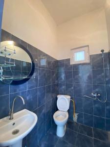 La salle de bains est pourvue de carrelage bleu, de toilettes et d'un lavabo. dans l'établissement Resort In Gonio, à Kvariati