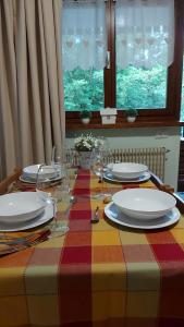 a table with plates and wine glasses on it at Appartamento incantevole con ampio balcone in Sella Nevea