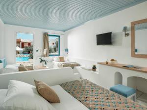 um quarto branco com uma cama, um sofá e uma televisão em Mitsis Cretan Village em Hersonissos