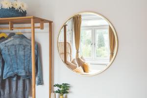 a round mirror hanging on a wall next to a window at Waves - Duplex Apartment Stoke Fleming in Stoke Fleming