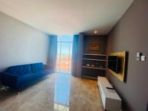 a living room with a blue couch and a tv at Stirling Suites Hotel & Serviced Apartment in Miri