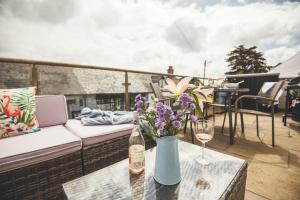 a table with a vase of flowers and a bottle of wine at Waves - Duplex Apartment Stoke Fleming in Stoke Fleming