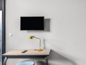 a desk with a lamp and a tv on a wall at Numa Prague Root in Prague