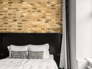 a bedroom with a brick wall and a bed with pillows at Numa Prague Root in Prague