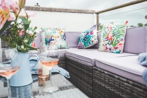 a couch on a balcony with flowers and wine glasses at Waves - Duplex Apartment Stoke Fleming in Stoke Fleming
