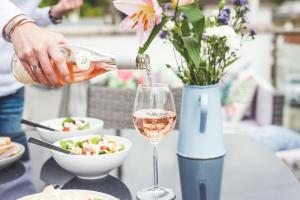 a person pouring wine into a glass on a table at Waves - Duplex Apartment Stoke Fleming in Stoke Fleming