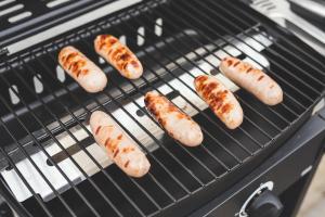 a bunch of sausages cooking on a grill at Waves - Duplex Apartment Stoke Fleming in Stoke Fleming