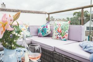 a couch on a porch with pillows and a glass of wine at Waves - Duplex Apartment Stoke Fleming in Stoke Fleming