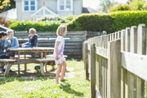 a little girl standing in front of a fence at Waves - Duplex Apartment Stoke Fleming in Stoke Fleming