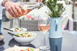 a person pouring wine into a bowl of food and a glass at Waves - Duplex Apartment Stoke Fleming in Stoke Fleming