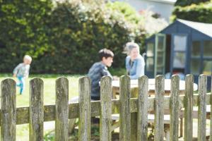 two boys sitting on a bench behind a fence at Waves - Duplex Apartment Stoke Fleming in Stoke Fleming