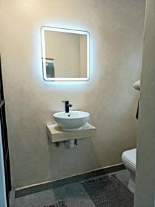 baño con lavabo y espejo en la pared en Lazy Days Apartments - Jeffreys Bay, en Jeffreys Bay