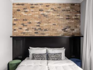 a bed with a black headboard and a brick wall at Numa Prague Root in Prague