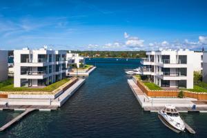 a river with two buildings and a boat in the water at Grano Solmarina - Marina Residence SPA&Wellness in Wiślinka