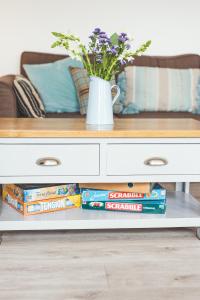 a coffee table with books and a vase with flowers at Waves - Duplex Apartment Stoke Fleming in Stoke Fleming