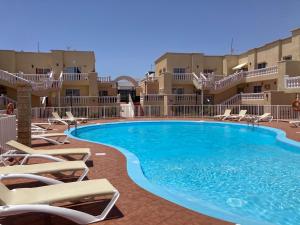 einen großen Pool mit Liegestühlen vor den Gebäuden in der Unterkunft Las Arenas caleta de fuste in Caleta de Fuste