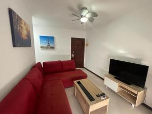 sala de estar con sofá rojo y TV de pantalla plana en Vacacional Arbelo Golf, en San Miguel de Abona