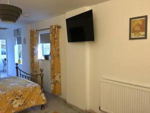a bedroom with a bed and a flat screen tv on the wall at Daffodil House Annex, Cynghordy, West Wales in Llandovery