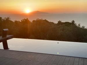 einen Sonnenuntergang von der Terrasse eines Hauses mit einer Bank in der Unterkunft “CapriOleum” esclusive place in Anacapri