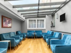 a waiting room with blue chairs and a tv at Numa Prague Root in Prague