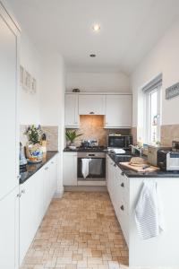 a kitchen with white cabinets and black counter tops at Waves - Duplex Apartment Stoke Fleming in Stoke Fleming