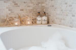 a bath tub with two bottles and candles on it at Waves - Duplex Apartment Stoke Fleming in Stoke Fleming